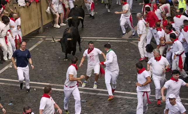 Revelers run with bulls from Fuente Ymbro ranch during the first day of the running of the bulls at the San Fermín fiestas in Pamplona, Spain, Monday, July 7, 2025. (AP Photo/Miguel Oses)