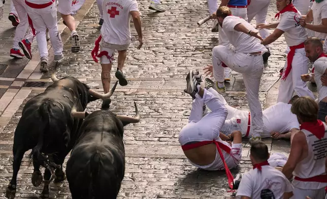 Revelers run with bulls from Fuente Ymbro ranch during the first day of the running of the bulls at the San Fermín fiestas in Pamplona, Spain, Monday, July 7, 2025. (AP Photo/Miguel Oses)