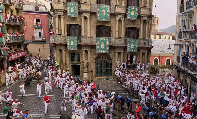 Revelers run with bulls from Fuente Ymbro ranch during the first day of the running of the bulls at the San Fermín fiestas in Pamplona, Spain, Monday, July 7, 2025. (AP Photo/Miguel Oses)