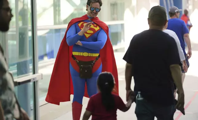 Comic-Con volunteer Chris Perry, of San Diego, waves to a young attendee before the 2025 Comic-Con International Preview Night on Wednesday, July 23, 2025, in San Diego. (AP Photo/Chris Pizzello)
