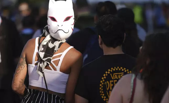 A cosplayer wears her mask backwards as she waits in line with other attendees before the 2025 Comic-Con International Preview Night on Wednesday, July 23, 2025, in San Diego. (AP Photo/Chris Pizzello)
