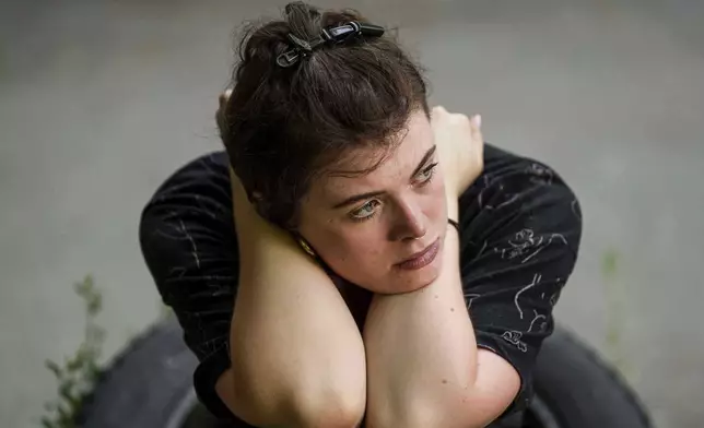 A young woman sits near her residential house damaged by a Russian strike in Kyiv, Ukraine, on Friday, July 4, 2025. (AP Photo/Evgeniy Maloletka)