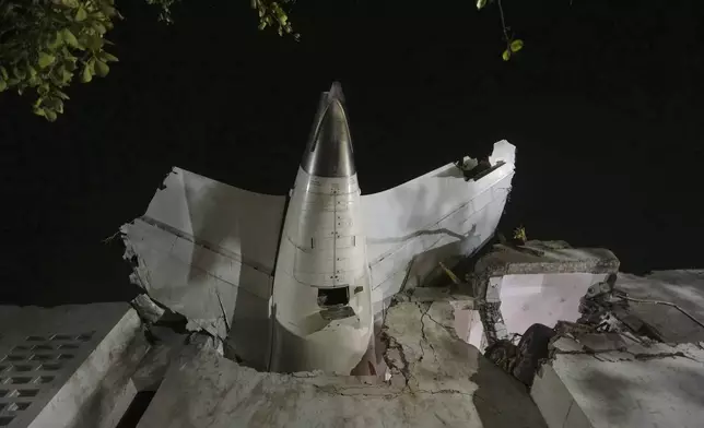 The tail of the airplane is seen stuck in a building at the site of an airplane that crashed in India's northwestern city of Ahmedabad in Gujarat state, Thursday, June 12, 2025. (AP Photo/Ajit Solanki)