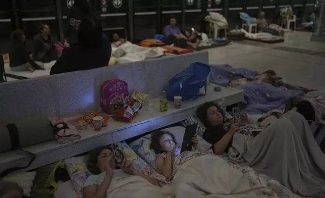 People take shelter in an underground metro station as a precaution against possible Iranian missile attacks, in Ramat Gan, near Tel Aviv, Israel, Tuesday, June 17, 2025. (AP Photo/Oded Balilty)