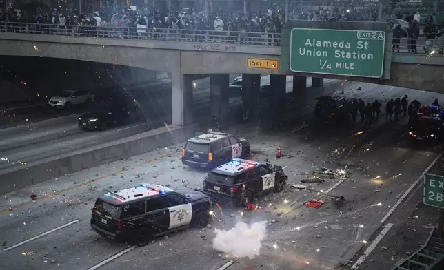 EDS NOTE: OBSCENITY A flash bomb explodes on the 101 Freeway near the metropolitan detention center of downtown Los Angeles, Sunday, June 8, 2025, following last night's immigration raid protest. (AP Photo/Eric Thayer)