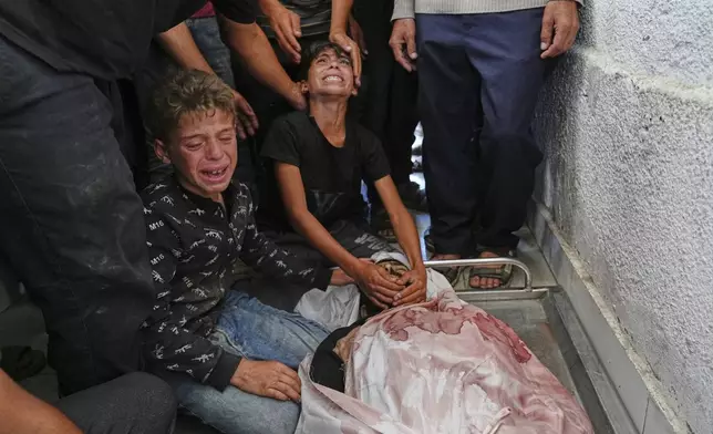 Palestinian children mourn over the body of their father, Mohammed Ghaben, who was killed while heading to an aid distribution hub, in Gaza City, Wednesday, June 18, 2025. (AP Photo/Jehad Alshrafi)