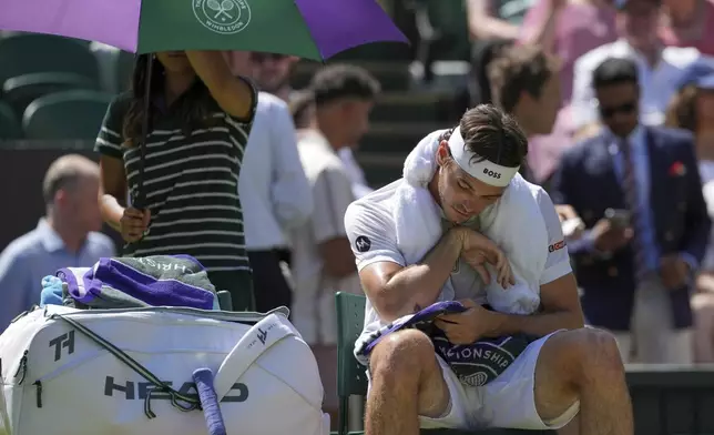 Taylor Fritz of the U.S. checks on his cut on his elbow in a break in his match against Spain's Carlos Alcaraz in a men's singles semifinal at the Wimbledon Tennis Championships in London, Friday, July 11, 2025. (AP Photo/Kin Cheung)