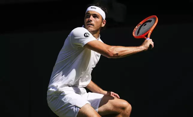 Taylor Fritz of the U.S. returns to Carlos Alcaraz of Spain during the men's semifinal singles match at the Wimbledon Tennis Championships in London, Friday, July 11, 2025.(AP Photo/Joanna Chan)