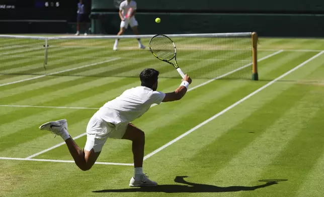 Carlos Alcaraz of Spain returns the ball to Taylor Fritz of the U.S. during the men's semifinal singles match at the Wimbledon Tennis Championships in London, Friday, July 11, 2025.(AP Photo/Kirsty Wigglesworth)