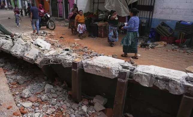 Residents walk past debris from damaged houses in Santa Maria de Jesus, Guatemala, Wednesday, July 9, 2025, following dozens of earthquakes and aftershocks that were recorded in a matter of hours. (AP Photo/Moises Castillo)