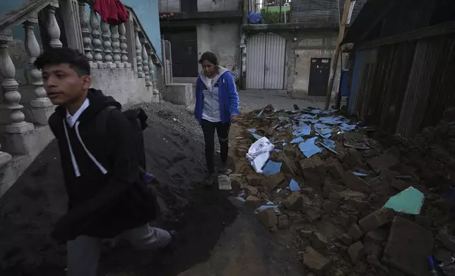Neighbors walk past the rubble of a damaged house in Palin, Guatemala, Wednesday, July 9, 2025, after a series of earthquakes with magnitudes ranging from 3.0 to 5.6, according to authorities. (AP Photo/Moises Castillo)
