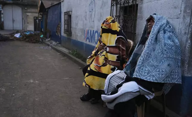 Residents sit outside their homes after dozens of earthquakes and aftershocks were recorded in a matter of hours in Palin, Guatemala, early Wednesday, July 9, 2025. (AP Photo/Moises Castillo)