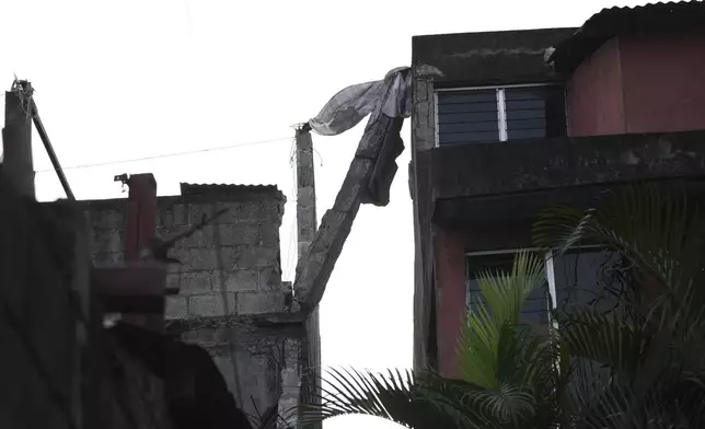 A concrete column leans over from a partially damaged house after dozens of earthquakes and aftershocks were recorded in a matter of hours in Palin, Guatemala, early Wednesday, July 9, 2025. (AP Photo/Moises Castillo)