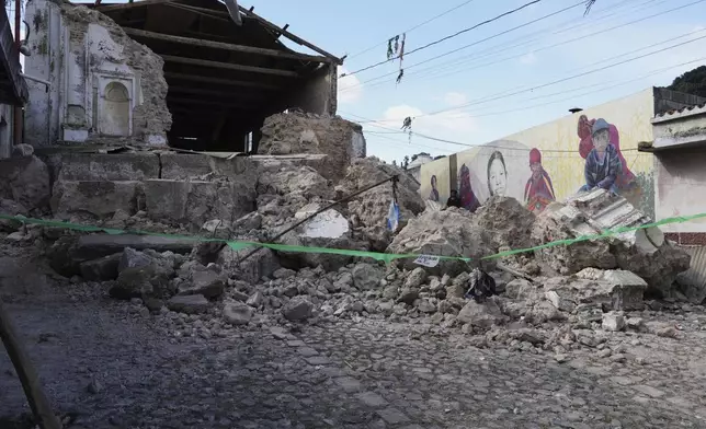 A man walks past the damaged Catholic Church El Calvario in Santa Maria de Jesus, Guatemala, Wednesday, July 9, 2025, following dozens of earthquakes and aftershocks that were recorded in a matter of hours. (AP Photo/Moises Castillo)