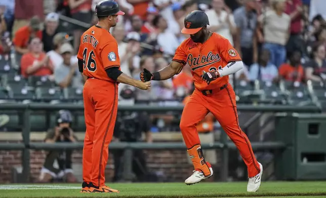 Baltimore Orioles' Cedric Mullins, right, celebrates with interim third base/infield coach Buck Britton (46) after hitting a three-run home run during the fourth inning of a baseball game against the Colorado Rockies, Saturday, July 26, 2025, in Baltimore. (AP Photo/Stephanie Scarbrough)