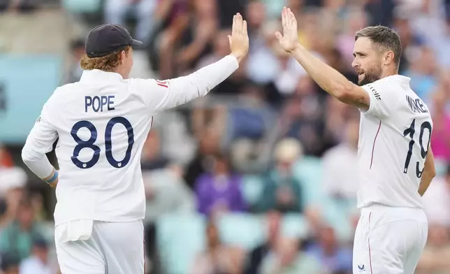 England's Chris Woakes, right, celebrates with England's captain Ollie Pope after the dismissal of India's KL Rahul during the first day of the fifth cricket test match between England and India at The Kia Oval in London, Thursday, July 31, 2025. (AP Photo/Kirsty Wigglesworth)