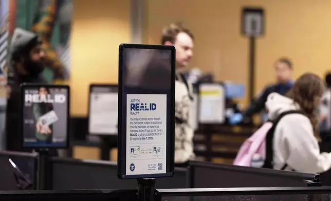 FILE - A sign for Real ID is seen as people walk through the security line at Anchorage airport, June 2, 2025, in Deadhorse, Alaska. (AP Photo/Jenny Kane, File)