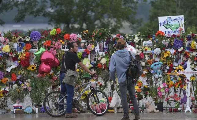Visitors place items on a memorial wall for flood victims, Sunday, July 13, 2025, in Kerrville, Texas. (AP Photo/Eric Gay)