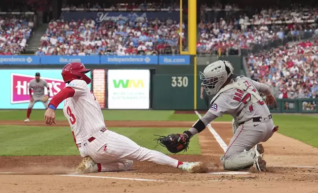 Philadelphia Phillies' Bryce Harper, left, scores past Boston Red Sox catcher Carlos Narváez on a catcher's interference call during the first inning of a baseball game Tuesday, July 22, 2025, in Philadelphia. (AP Photo/Matt Slocum)
