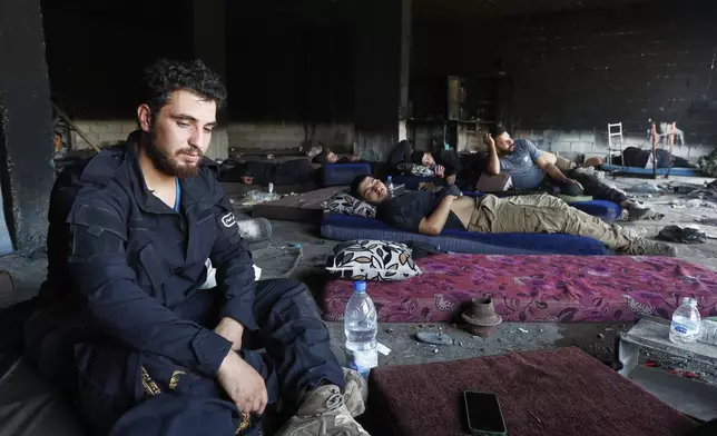 Syrian security forces rest inside a burned out shop as they deploy in Mazraa village on the outskirts of Sweida city, in southern Syria, Sunday, July 20, 2025. (AP Photo/Omar Sanadiki)