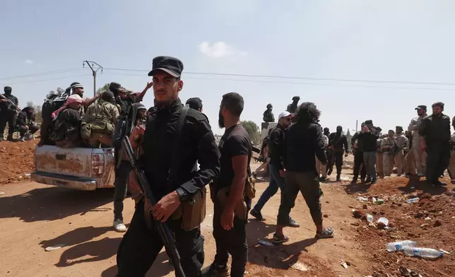 Syrian government security forces block Bedouin fighters, background, from entering Sweida province, in Busra al-Harir village, southern Syria, Sunday, July 20, 2025. (AP Photo/Omar Sanadiki)