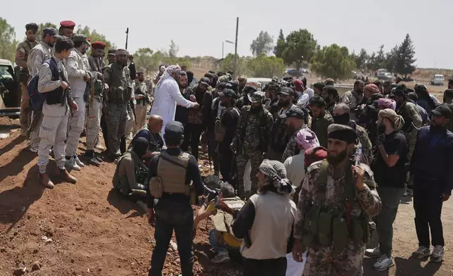Bedouin fighters, right, gather as Syrian government security forces, left, block them from entering Sweida province, in Busra al-Harir village, southern Syria, Sunday, July 20, 2025. (AP Photo/Ghaith Alsayed)