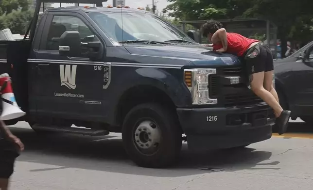 In this photo provided by WHAS-11 News, a protestor jumps on the hood of a Louisville Water truck outside the federal courthouse where ex-Kentucky police officer Brett Hankison, convicted of using excessive force during the deadly Breonna Taylor raid, is taking place, Monday, July 21, 2025, in Louisville, Ky. (Alyssa Newton/WHAS-11 News via AP)