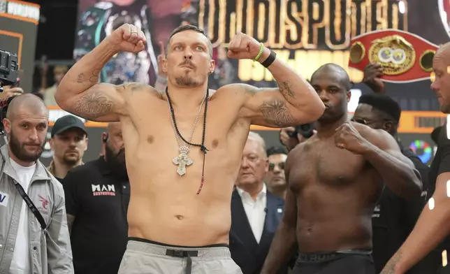 Ukraine's Oleksandr Usyk poses during the weigh-in in London, Friday, July 18, 2025 ahead of his world heavyweight boxing title fight against Britain's Daniel Dubois, right, on Saturday (AP Photo/Kin Cheung)