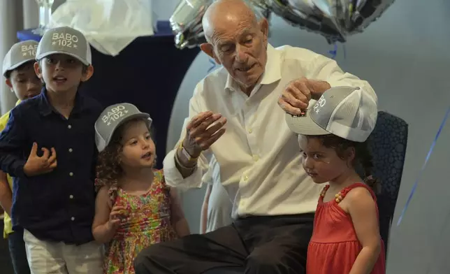 Harold Terens gifts customized hats to his great grandchildren during his 102 birthday party Saturday, July 26, 2025, in Delray Beach, Fla. (AP Photo/Marta Lavandier)