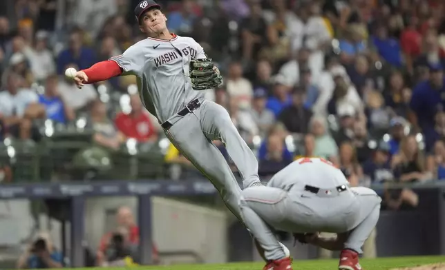 Washington Nationals' Brady House, left, throws a runner out over Nationals' Mitchell Parker as he ducks during the fourth inning of a baseball game against the Milwaukee Brewers, Friday, July 11, 2025, in Milwaukee. (AP Photo/Aaron Gash)
