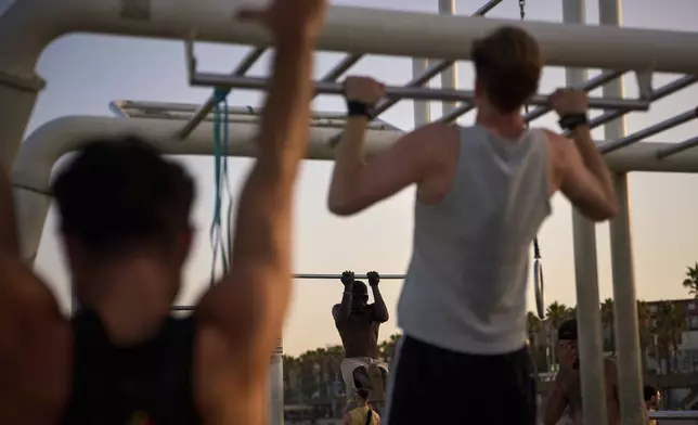 People work out in an open-air gym next to the beach in Barcelona, Spain, Tuesday, June 25, 2025. (AP Photo/Emilio Morenatti)