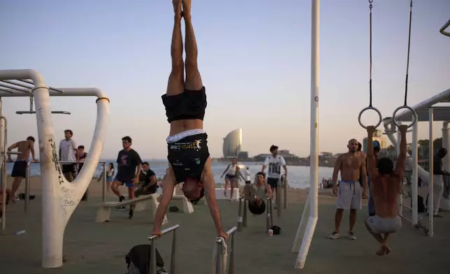 People work out in an open-air gym next to the beach in Barcelona, Spain, Tuesday, June 25, 2025. (AP Photo/Emilio Morenatti)