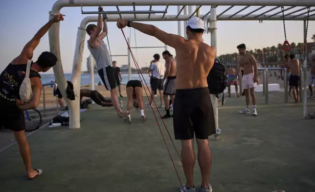 People work out in an open-air gym next to the beach in Barcelona, Spain, Tuesday, June 25, 2025. (AP Photo/Emilio Morenatti)
