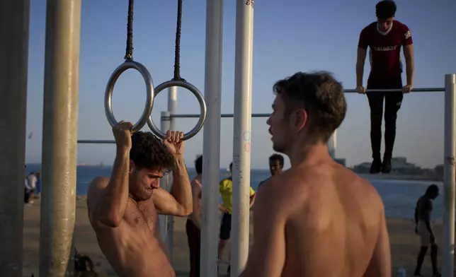 People work out in an open-air gym next to the beach in Barcelona, Spain, Tuesday, June 25, 2025. (AP Photo/Emilio Morenatti)