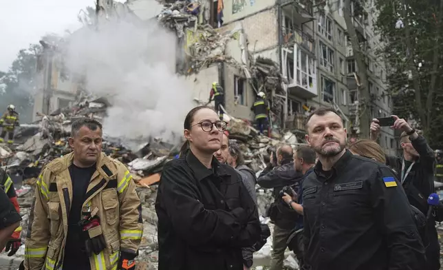 Ukraine's Prime Minister Yuliia Svyrydenko, centre, and Interior Minister Ihor Klymenko, right, visit the site of a multi-storey residential building destroyed by a Russian missile attack in Kyiv, Ukraine, Thursday, July 31, 2025. (AP Photo/Efrem Lukatsky)