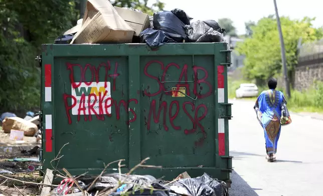 A woman walks past a garbage collection site, Wednesday, July 9, 2025, in Philadelphia. (AP Photo/Matt Slocum)