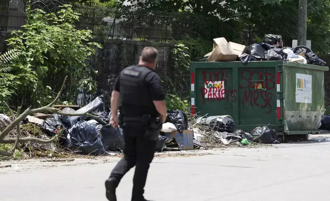 A police officer walks past a garbage collection site, Wednesday, July 9, 2025, in Philadelphia. (AP Photo/Matt Slocum)