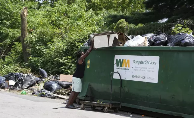 A man drops off trash at a garbage collection site, Wednesday, July 9, 2025, in Philadelphia. (AP Photo/Matt Slocum)