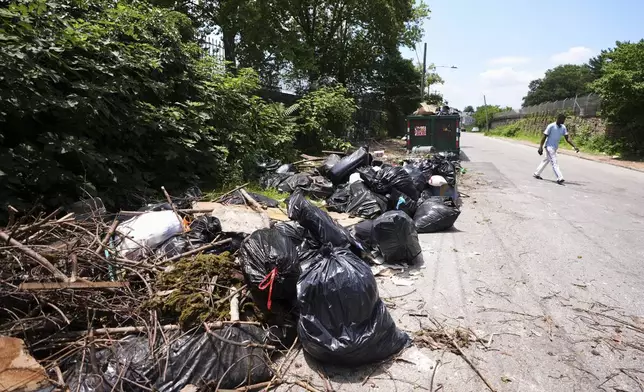 A man walks past a garbage collection site, Wednesday, July 9, 2025, in Philadelphia. (AP Photo/Matt Slocum)