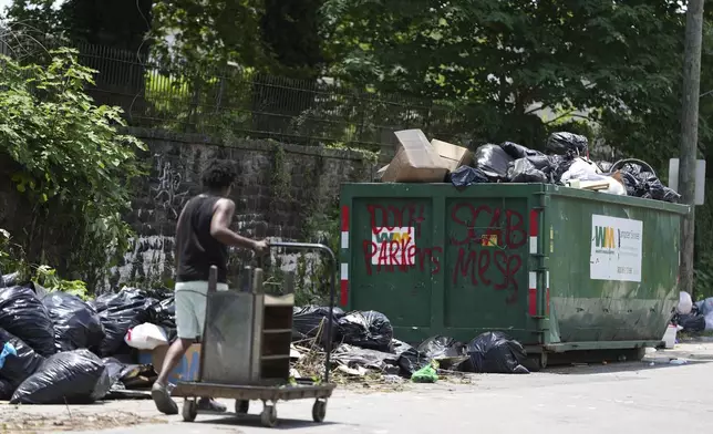 A man takes trash to a garbage collection site, Wednesday, July 9, 2025, in Philadelphia. (AP Photo/Matt Slocum)