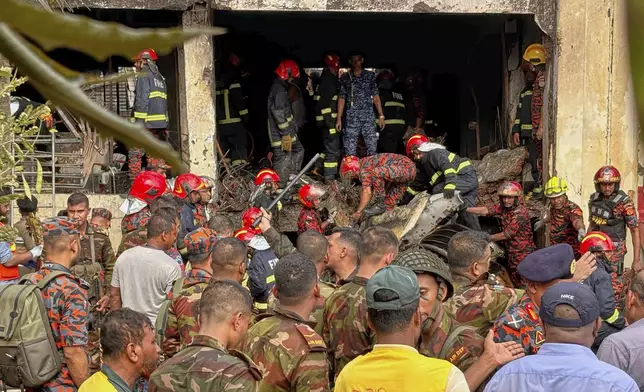 Firemen check the wreckage of a Bangladesh Air Force training aircraft that crashed onto a school campus in Dhaka, Bangladesh, Monday, July 21, 2025. (AP Photo/Al-emrun Garjon)