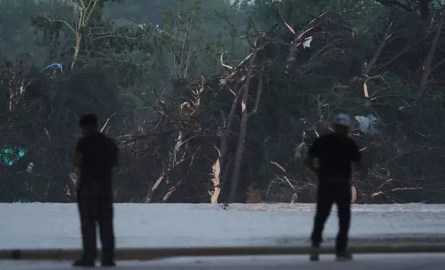 Onlookers survey damage caused along the Guadalupe River after a flash flood swept through the area, Friday, July 4, 2025, in Kerrville, Texas. (AP Photo/Eric Gay)