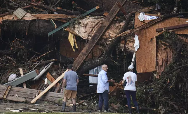 People look at debris on the banks of the Guadalupe River after a flash flood swept through the area Saturday, July 5, 2025, in Hunt, Texas. (AP Photo/Julio Cortez)