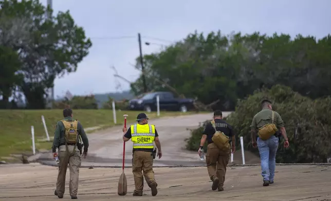 Deputies walk along a road near the Guadalupe River after a flash flood swept through the area Saturday, July 5, 2025, in Ingram. (AP Photo/Julio Cortez)