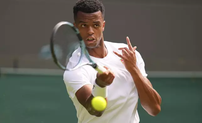 Giovanni Mpetshi Perricard of France returns the ball to Taylor Fritz of the U.S. during their first round men's singles match at the Wimbledon Tennis Championships in London, Tuesday, July 1, 2025.(AP Photo/Kirsty Wigglesworth)