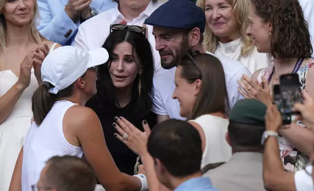 Courteney Cox, center, and Johnny McDaid celebrate with Poland’s Iga Swiatek as she greets her coaches, friends and family after beating Amanda Anisimova of the U.S. to win the women’s singles final at the Wimbledon Tennis Championships in London, Saturday, July 12, 2025.(Andrew Matthews, PA via AP)