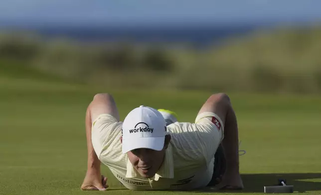 Matt Fitzpatrick of England lies down on the 15th green to look at the lie of his putt during the third round of the British Open golf championship at the Royal Portrush Golf Club, Northern Ireland, Saturday, July 19, 2025. (AP Photo/Jon Super)