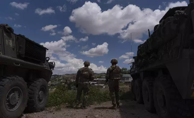 Two U.S. Army soldiers stand between Stryker combat vehicles as they watch over the U.S.-Mexico border fence from a hilltop in Nogales, Ariz., Tuesday, July 22, 2025. (AP Photo/Jae C. Hong)