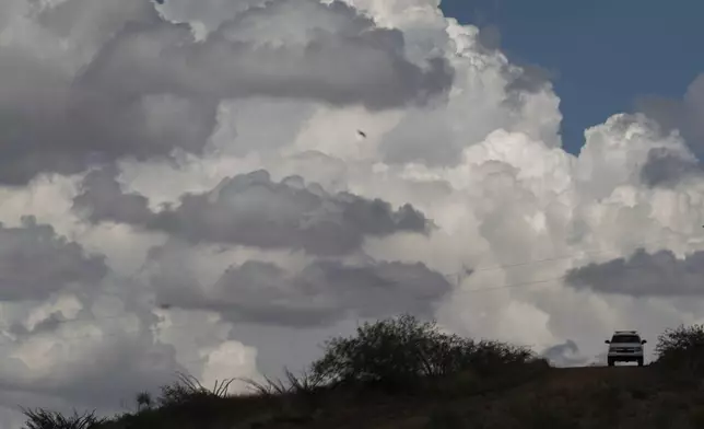 A U.S. Border Patrol vehicle travels along a trail beneath storm clouds near the U.S.-Mexico border fence, Tuesday, July 22, 2025, in Nogales, Ariz. (AP Photo/Jae C. Hong)