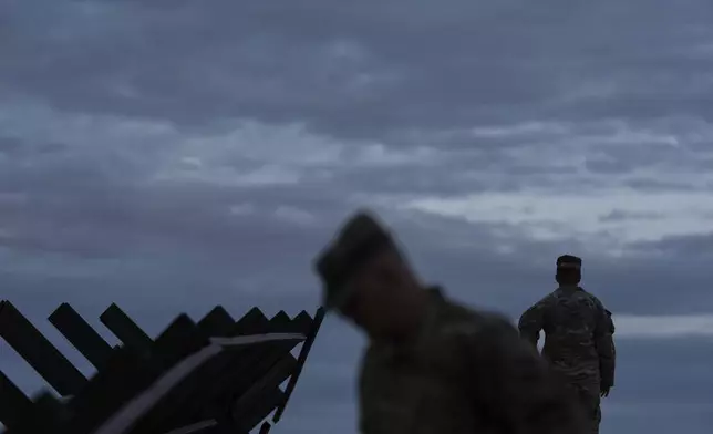 U.S Army personnel stand along barriers forming part of the U.S.-Mexico border fence on Wednesday, July 23, 2025, in Sunland Park, N.M. (AP Photo/Jae C. Hong)